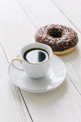 Chocolate top donut and black coffee on a table top