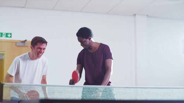 Two male players comically losing a point in table tennis