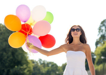 smiling young woman in sunglasses with balloons