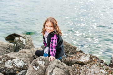 Naklejka premium Outdoor portrait of a cute little girl playing next to lake