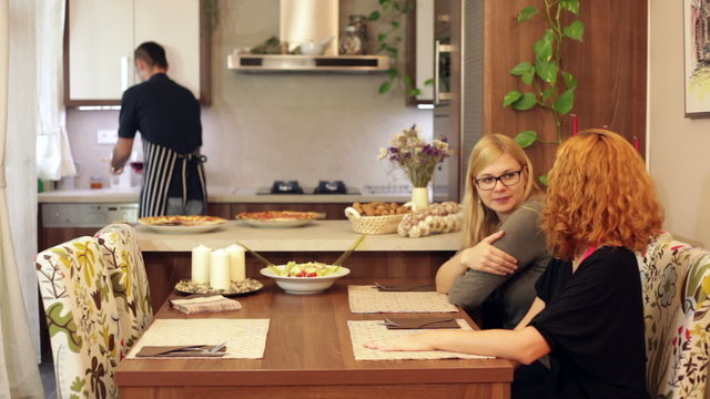 Man serving wine to women at home