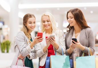 happy women with smartphones and shopping bags