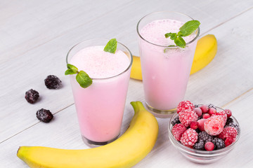 Frozen summer berries milkshakes on white wooden background