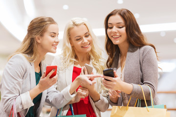 happy women with smartphones and shopping bags