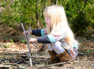 Cute Blond Girl Playing with Twigs on Ground