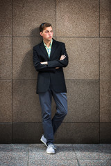 Young fashion man standing against the wall