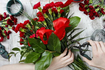 Fototapeta na wymiar Florist at work. Woman making bouquet of red carnations