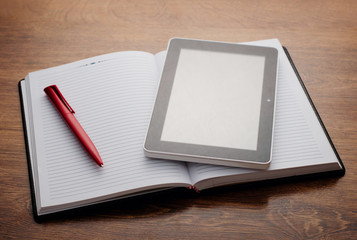 Tablet Device on Open Notebook at Wooden Table