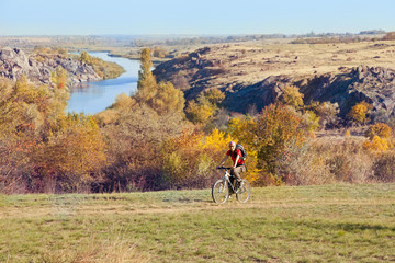 Woman riding a mountain bike on a rural  road on river backgroun