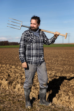 Landwirt mit Mistgabel auf seinem Feld