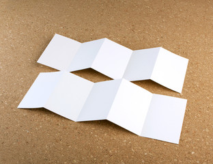 blank white folding paper flyer on a cork background