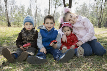 Children sit on the grass in the forest in the spring.