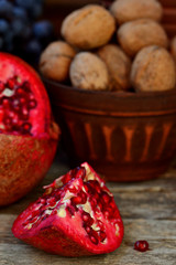 pomegranate, walnuts and glass of wine on a wooden background