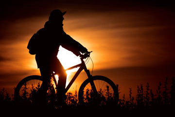 Велосипедист на берегу реки на закате Солнца