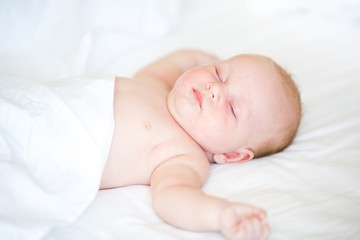 Peaceful newborn baby lying on a bed sleeping