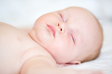 Peaceful newborn baby lying on a bed sleeping