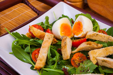Chicken and egg with vegetables in plate, close view