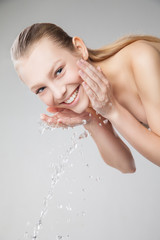 Beautiful woman washing her clean face with water
