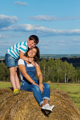 Naklejka na ściany i meble Little brother embracing his older sister sitting on a haystack 