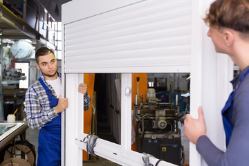 Two workers in uniform inspecting windows with shutter