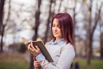 University girl in park reading a book