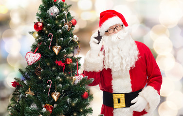 santa claus with smartphone and christmas tree