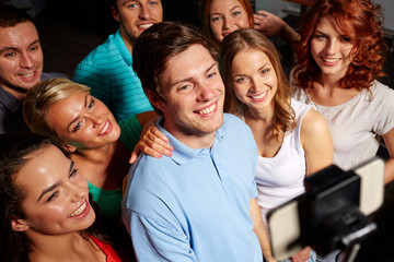 friends with smartphone taking selfie in club