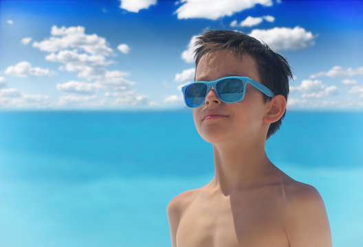 Portrait of young boy wearing sunglasses and posing by sea