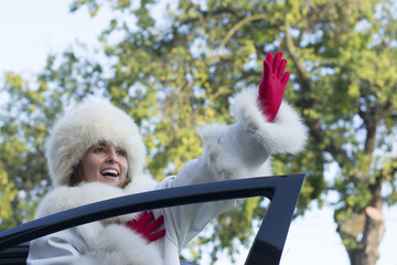 Smiling woman waving from a car window