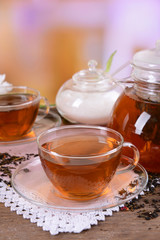 Teapot and cups of tea on table on light background