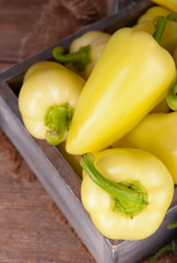 Yellow peppers in crate with sackcloth on table close up