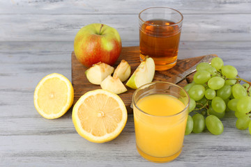 glasses of juice with fresh fruits on grey wooden table