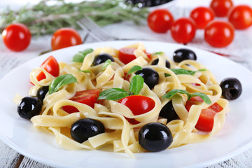 Spaghetti with tomatoes, olives and basil leaves
