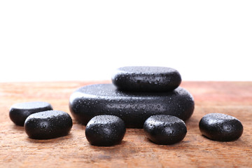 Spa stones with drops on table on light background