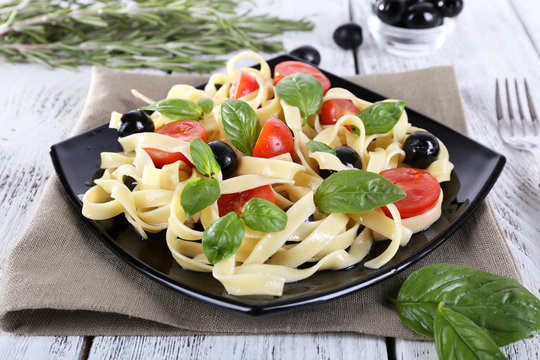 Spaghetti with tomatoes, olives and basil leaves
