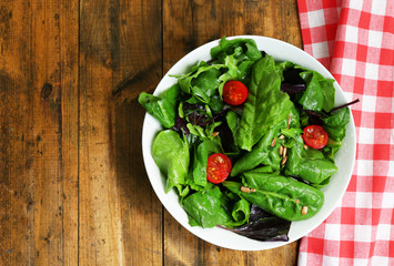 Fresh green salad in bowl on wooden table