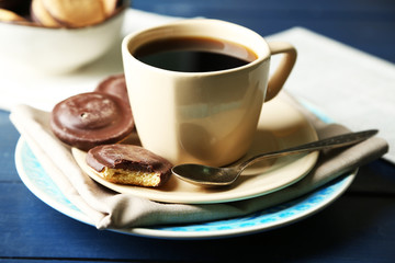 Cup of coffee with tasty cookies on color wooden background