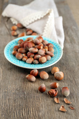 Hazelnuts on plate on wooden background
