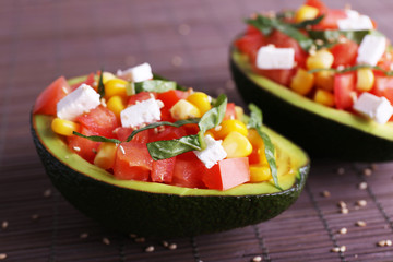 Tasty salad in avocado on bamboo napkin close-up