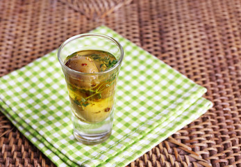 Green olives in oil with spices and rosemary in glass on table