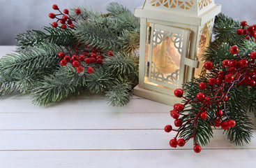 Lantern for candle with berries and conifer on white planks © samiramay
