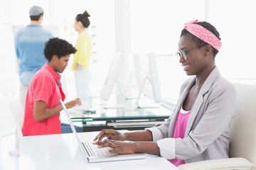 Young creative woman using laptop at desk