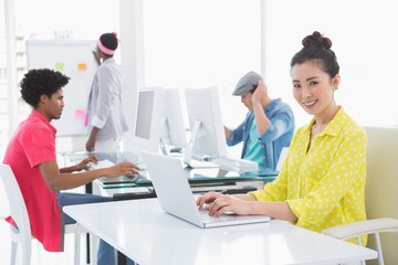 Young creative woman using laptop at desk