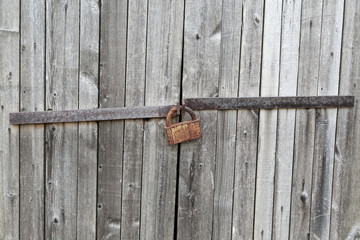 Old wooden door locked with rusty padlock