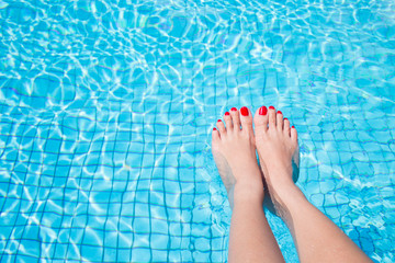 woman legs with red nail in swimming pool