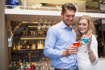 Cute couple standing and drinking cocktails