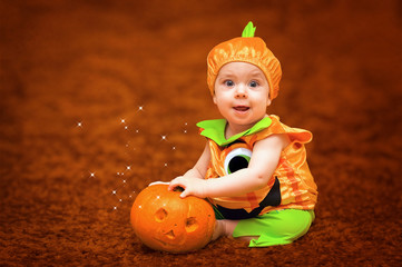 Child in pumpkin suit on dark background with pumpkin