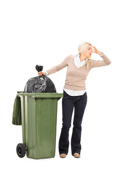 Disgusted woman standing next to a trash can