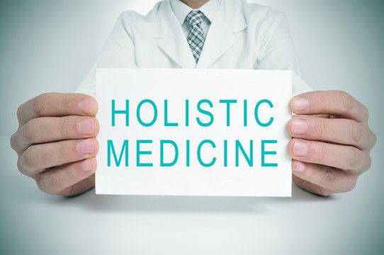 doctor with a signboard with the text holistic medicine