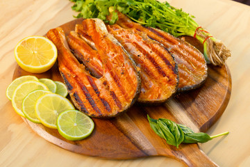 Grilled salmon fillet with lime and parsley on a wooden board